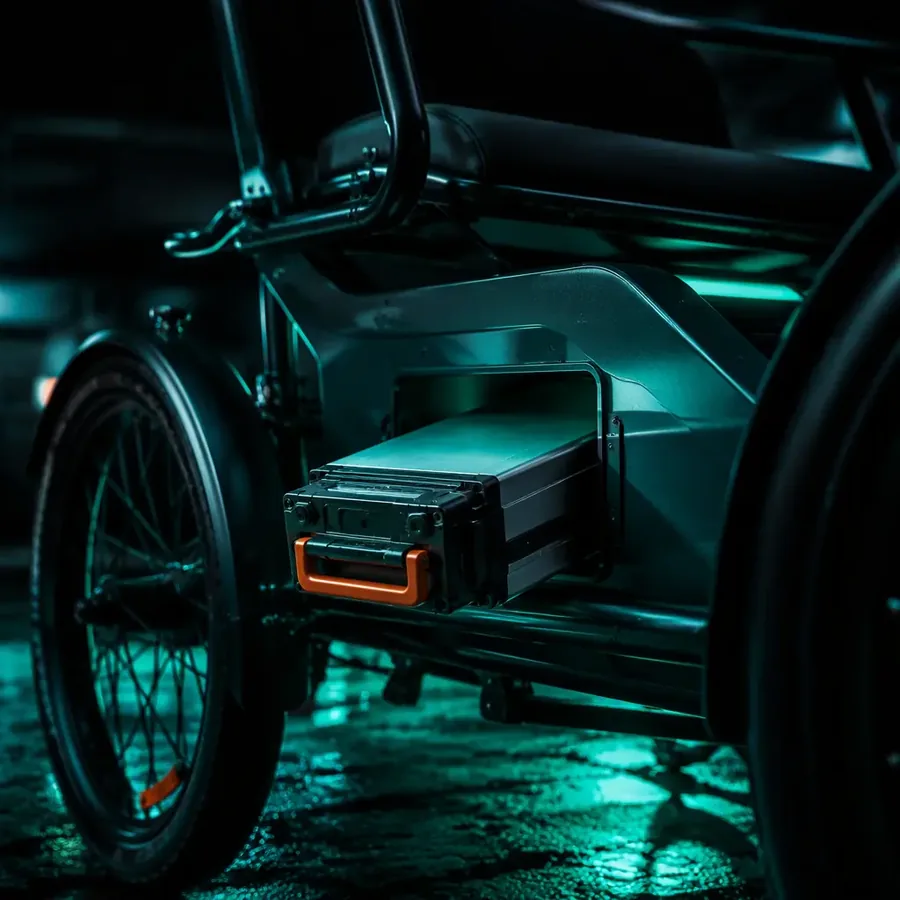 Removable lithium battery pack on an electric cargo tricycle frame, with the charging connection point in view